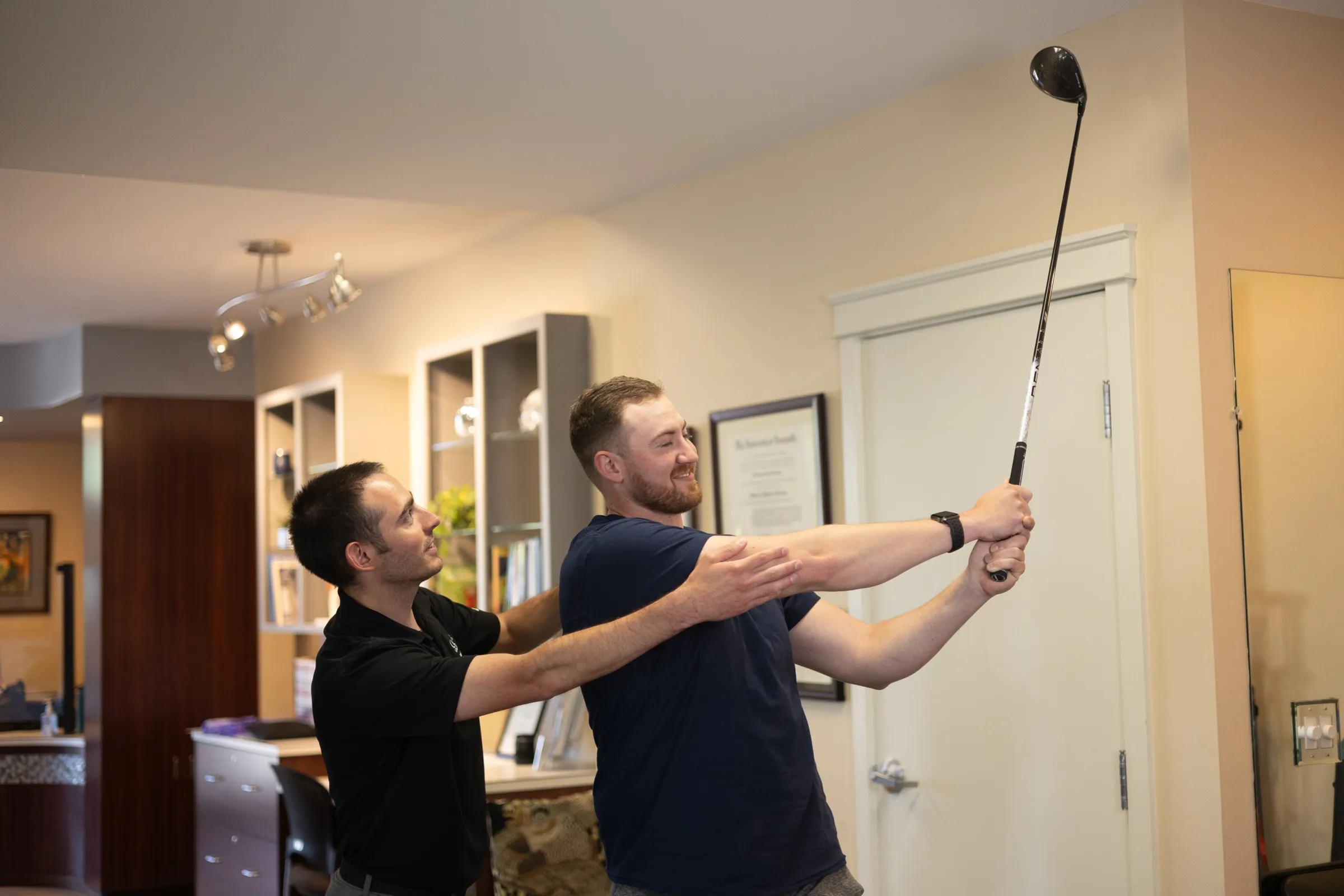 An Encore therapist guiding a patient's golf swing in the clinic