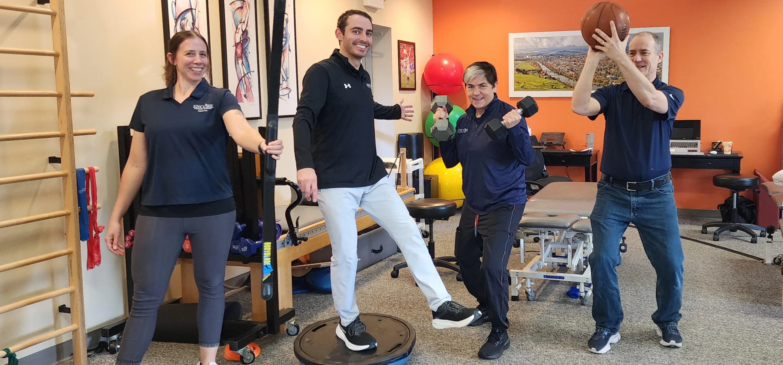 The Encore team posing with exercise equipment in the clinic gym