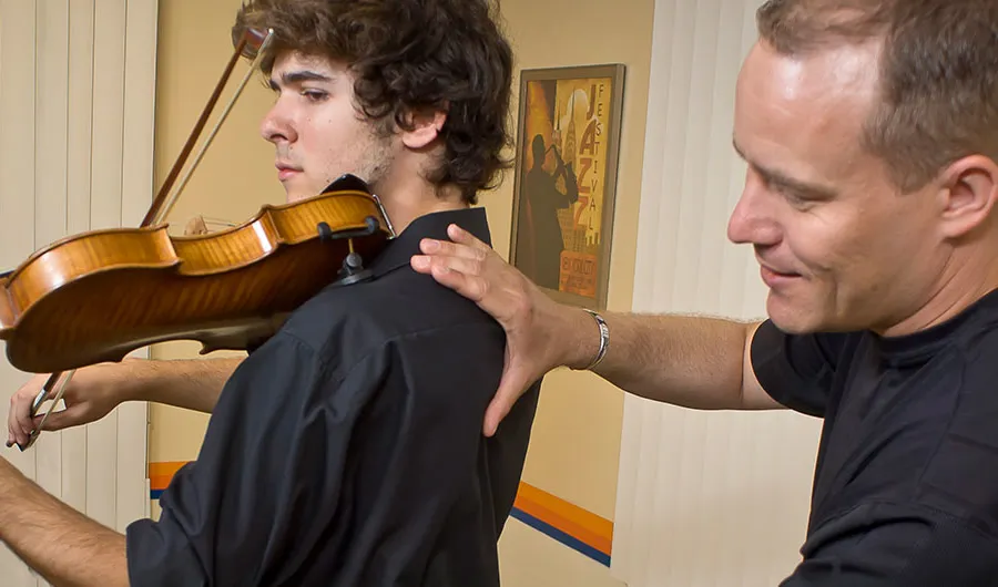Chris Guempel assessing a violinist’s shoulder and posture while they play